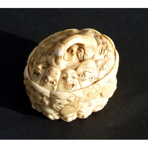 754 - A Chinese carved ivory box and cover, the surface profusely carved with images of faces, 5cms wide.