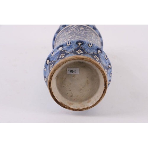 811 - An Iznik vase decorated with foliate scrolls on a blue ground, 31cms high.