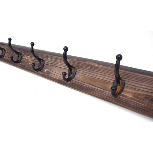 875 - A set of six vintage cast iron coat hooks on a wooden plinth, 98cms long.