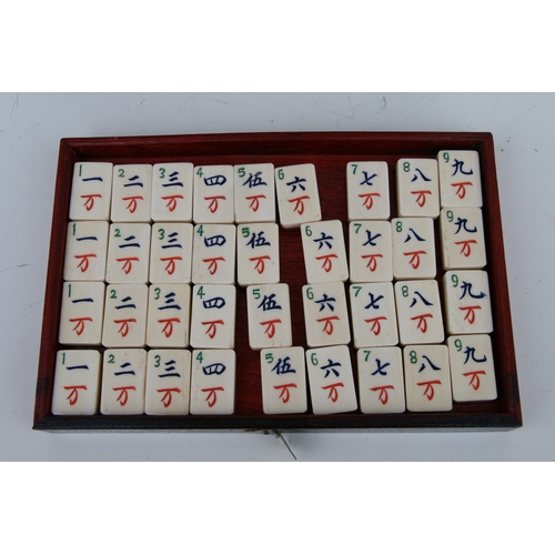 798 - A Chinese bone and bamboo Mah Jong set in a mother of pearl inlaid hardwood case, 24cms wide.