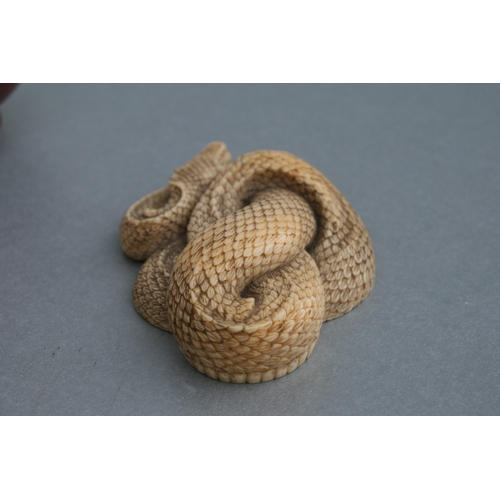 755 - A Chinese carved ivory figure in the form of a coiled snake, 4.5cms wide.