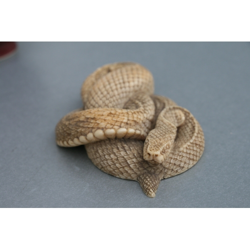 755 - A Chinese carved ivory figure in the form of a coiled snake, 4.5cms wide.