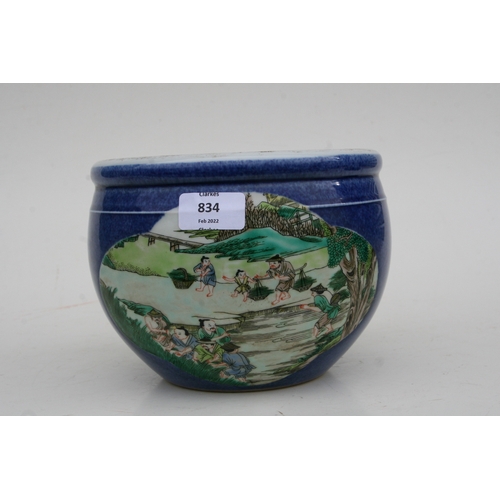 834 - A Chinese fish bowl of small proportions decorated with figures beside a pond, on a blue ground with... 