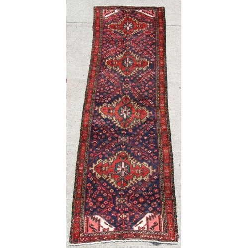 103 - A fine quality Persian hand knotted runner with four central guls on a red ground, 265 by 205cms (79... 