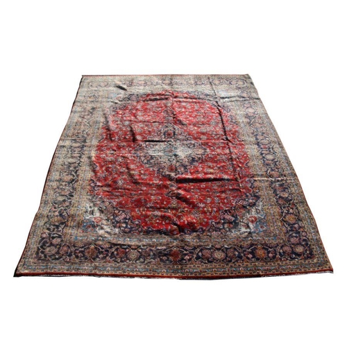 104 - A Persian Kashan woollen hand knotted carpet with foliate design on a red ground, 408 by 310cms (106... 