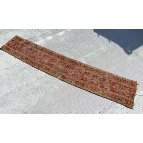 115 - A Turkish runner with repeated floral decoration on a red ground, 392 by 73cms.