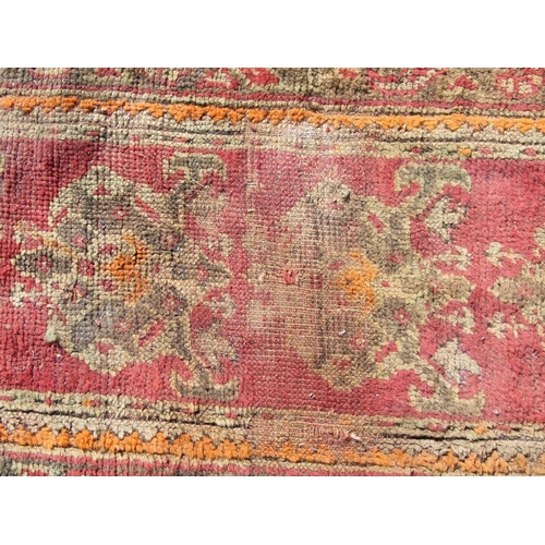 115 - A Turkish runner with repeated floral decoration on a red ground, 392 by 73cms.