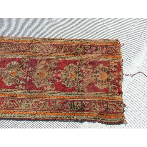 115 - A Turkish runner with repeated floral decoration on a red ground, 392 by 73cms.