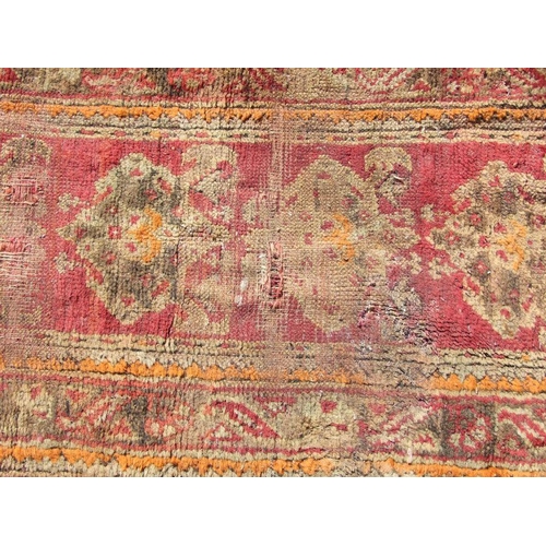 115 - A Turkish runner with repeated floral decoration on a red ground, 392 by 73cms.