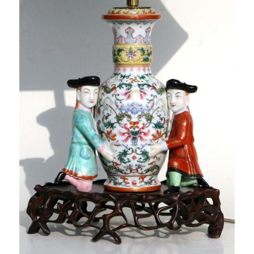 509 - A Chinese famille rose vase form lamp decorated with foliate scrolls being supported by western figu... 