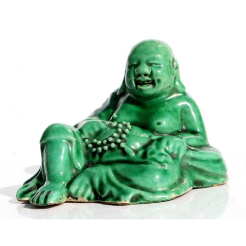 561 - A Chinese shiwan type pottery green glazed figure of a Buddha, 9cms wide.