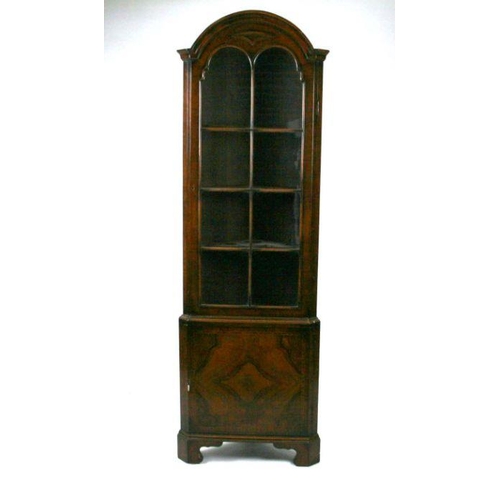 783 - A figured walnut corner display cabinet, the glazed door enclosing a shelved interior with cupboard ... 