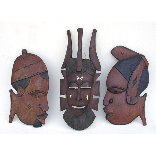 79 - An African hardwood mask, 59cms (23ins) high; together with two African wall plaques (3).