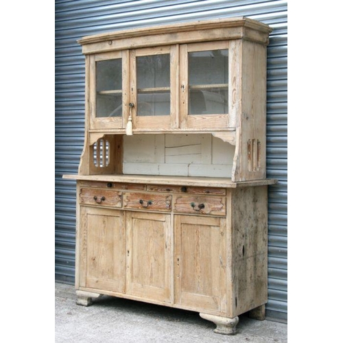 793 - A continental stripped pine dresser, the bowfronted superstructure with three glazed doors enclosing... 