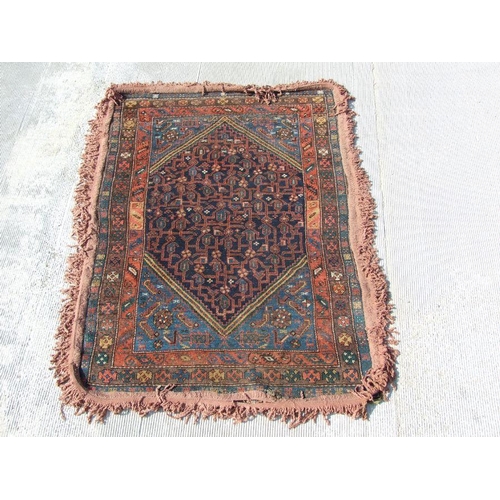 93 - A Persian rug with central medallion with repeating geometric shapes on a dark blue ground within a ... 