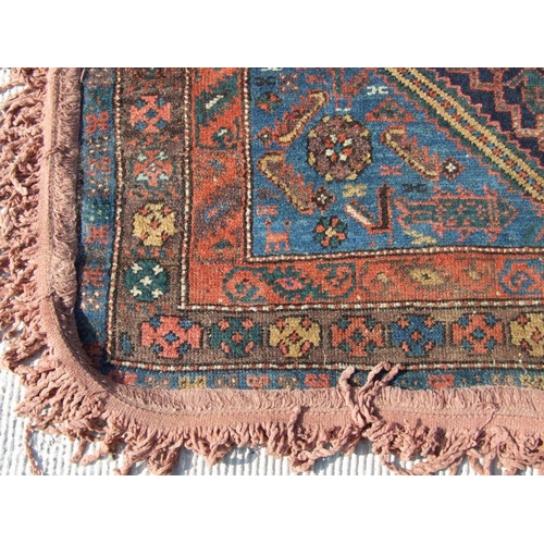 93 - A Persian rug with central medallion with repeating geometric shapes on a dark blue ground within a ... 