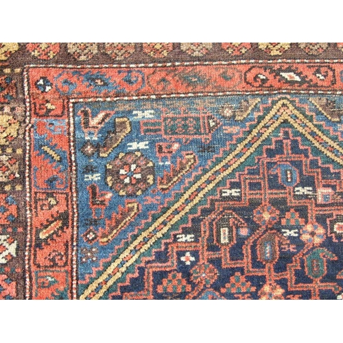 93 - A Persian rug with central medallion with repeating geometric shapes on a dark blue ground within a ... 