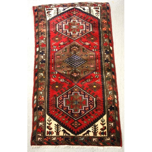 98 - A Persian Hamadan hand knotted woollen rug with stylised design within borders, on a red ground, 163... 