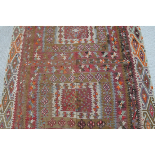 94 - A kilim rug with repeating geometric motifs on a mustard ground within a multi border, 152 by 317cms... 