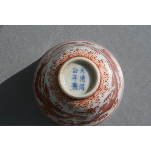 514 - A Chinese red oxide tea bowl decorated with dragons amongst clouds, six character blue mark to the u... 