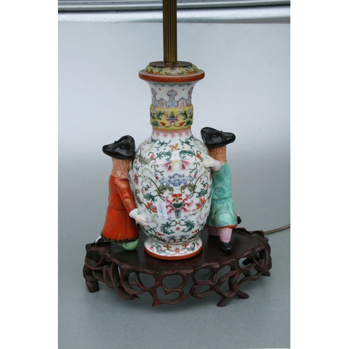 509 - A Chinese famille rose vase form lamp decorated with foliate scrolls being supported by western figu... 