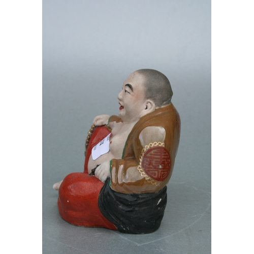 574 - A Chinese figure of a fat Buddha with glazed robes and bisque body, twin impressed seal marks to the... 