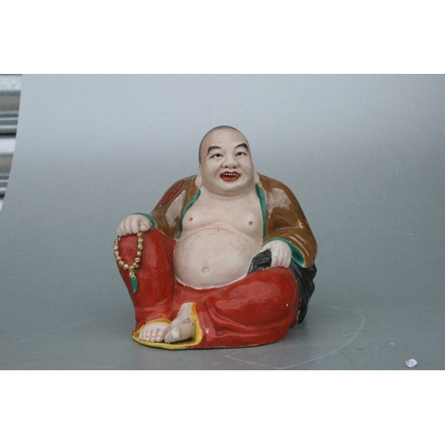 574 - A Chinese figure of a fat Buddha with glazed robes and bisque body, twin impressed seal marks to the... 