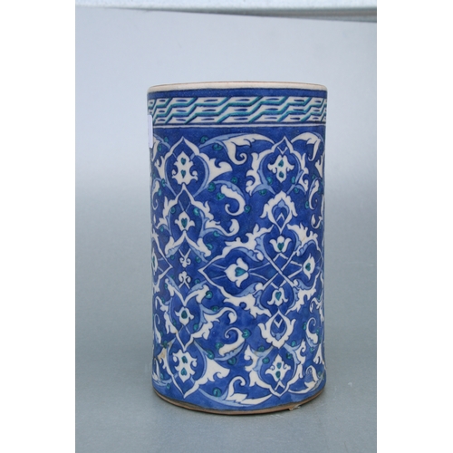 614 - A Turkish / Iznik pottery tankard decorated with foliate scrolls on a blue ground, 21cms high.