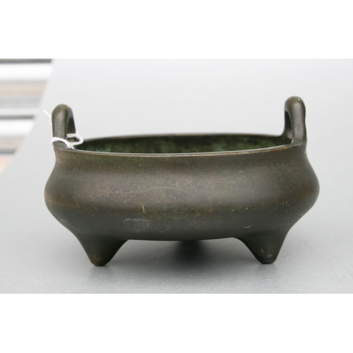 640 - A Chinese bronze two-handled censer on tripod legs, six character mark to the underside, 16cms diame... 