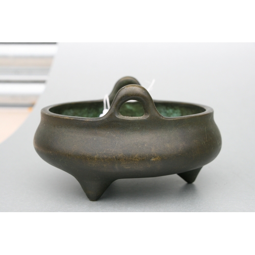 640 - A Chinese bronze two-handled censer on tripod legs, six character mark to the underside, 16cms diame... 