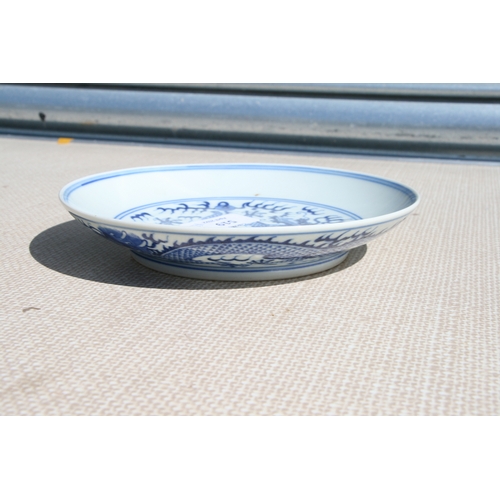 519 - A pair of Chinese blue & white shallow dishes decorated with dragons chasing a flaming pearl amongst... 