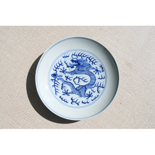 519 - A pair of Chinese blue & white shallow dishes decorated with dragons chasing a flaming pearl amongst... 