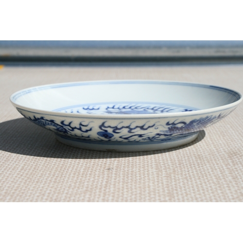 519 - A pair of Chinese blue & white shallow dishes decorated with dragons chasing a flaming pearl amongst... 