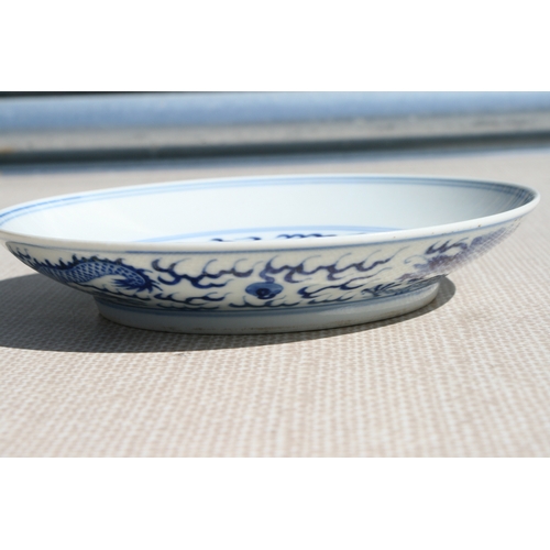 519 - A pair of Chinese blue & white shallow dishes decorated with dragons chasing a flaming pearl amongst... 