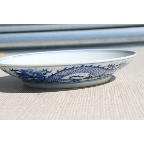 519 - A pair of Chinese blue & white shallow dishes decorated with dragons chasing a flaming pearl amongst... 