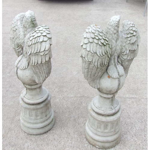 14 - A large pair of stoneware garden eagles perched on a sphere with their wings outswept, 97cms high (2... 