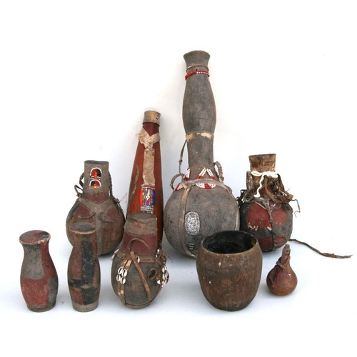 205 - A collection of African Tribal gourd water carriers, some with bead decoration and wooden cup lids, ... 