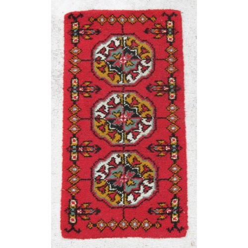 284 - A rug with repeating guls on a red ground, 140 by 70cms.