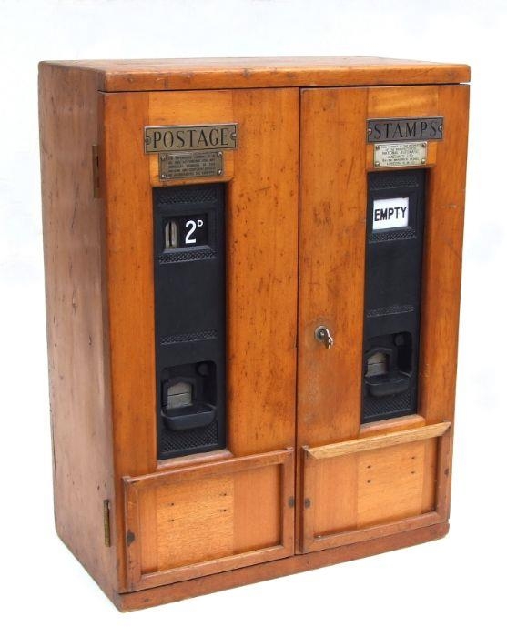 A mid 20th century mahogany stamp dispenser with two stamp