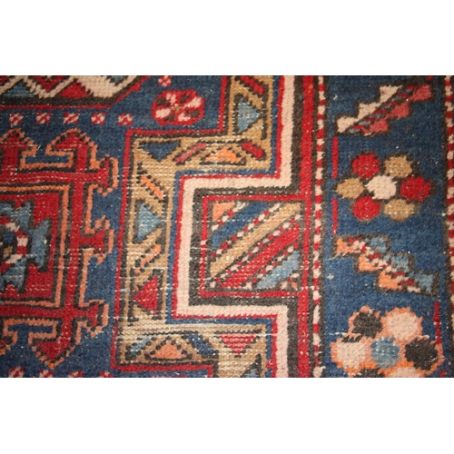 287 - A Persian Azari hand knotted woollen runner with five stylised guls within floral borders, on a blue... 