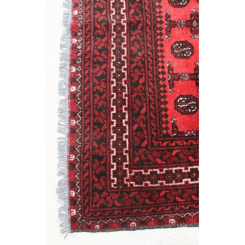 190 - A Persian Turkoman woollen hand knotted rug with repeat design on a red ground, 237 by 155cms.