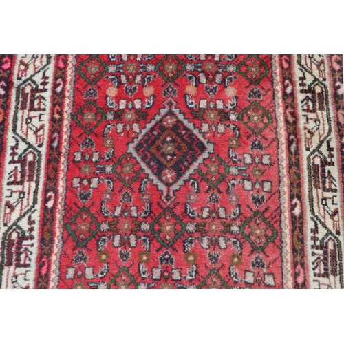 195 - A Persian runner with geometric design on a red ground within a multi border, 282 by 81cms.