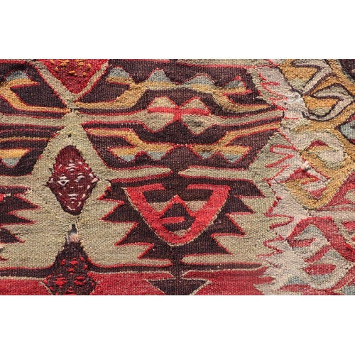 153E - A large kilim rug or wall hanging with repeat design on a beige ground, 365 by 139cms.
