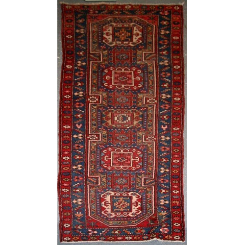 154 - A Persian Azari hand knotted woollen runner with five stylised guls within floral borders, on a blue... 