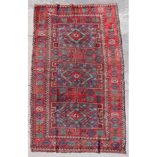 157 - A Persian Azari hand knotted woollen rug with geometric design on a red ground, 290 by 155cms (384).