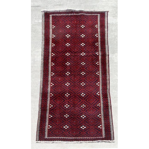 159 - A fine quality Persian Baluch woollen hand knotted runner with repeat gul medallions on a claret gro... 