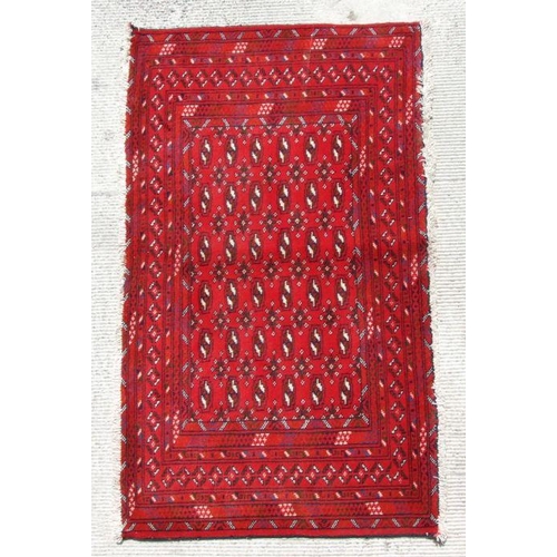 173 - A small Persian Turkoman rug with repeat stylised design on a red ground, 130 by 70cms.