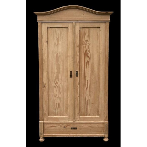 862 - A continental pine double wardrobe, the shaped cornice above two panelled doors, on bun front feet, ... 