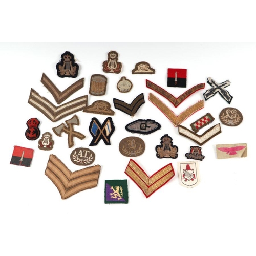 98 - A collection of cloth military shoulder titles and badges for various regiments and ranks.