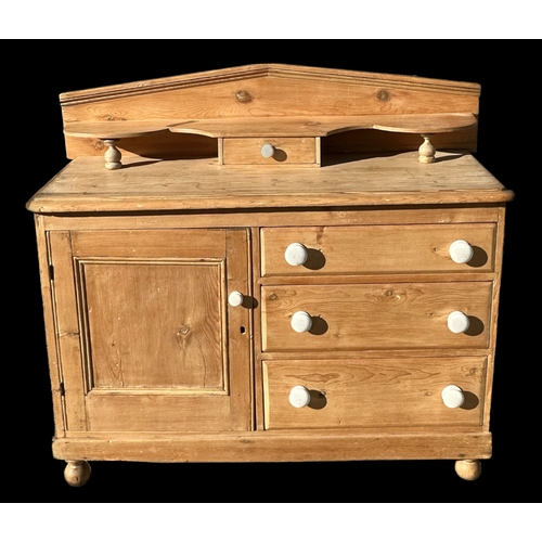 863 - A stripped pine cupboard with a gallery back with single shelf above three drawers flanked by a sing... 